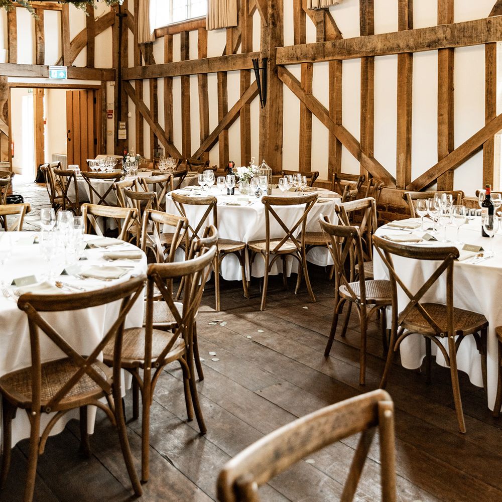 Rustic barn wedding venue complete with wooden beams and round tables covered in white table cloth