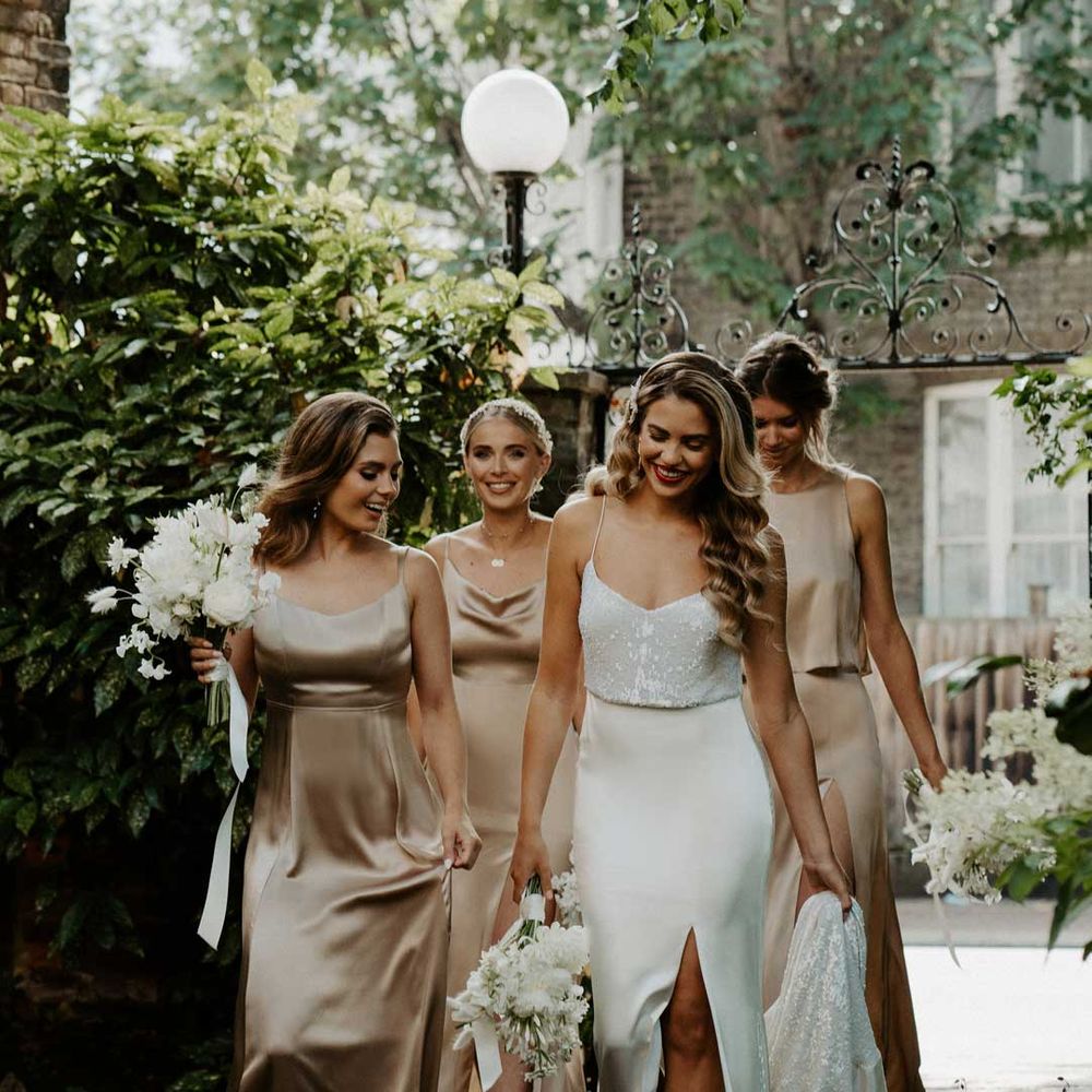 Bride in front slit satin strappy wedding dress walking with bridal party in Constellation Ame sleeveless champagne gold satin bridesmaid dresses 