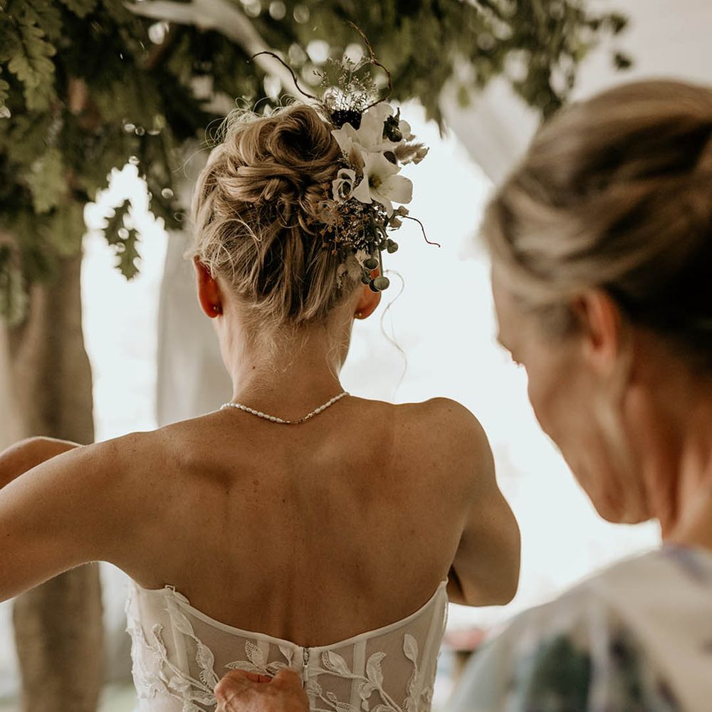 Bride wearing a strapless corset style wedding dress with dainty pearl necklace and updo decorated with flower hair accessories 