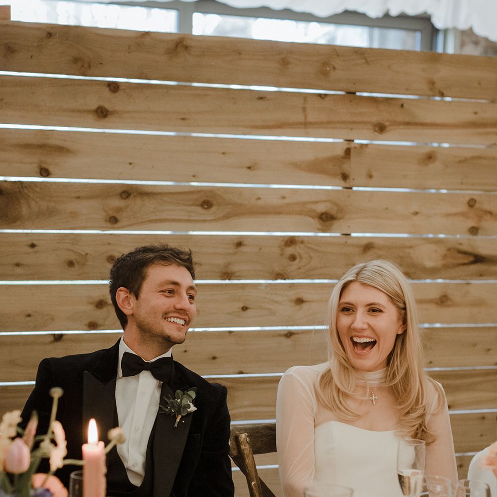 The bride and groom laugh together during the wedding speeches 