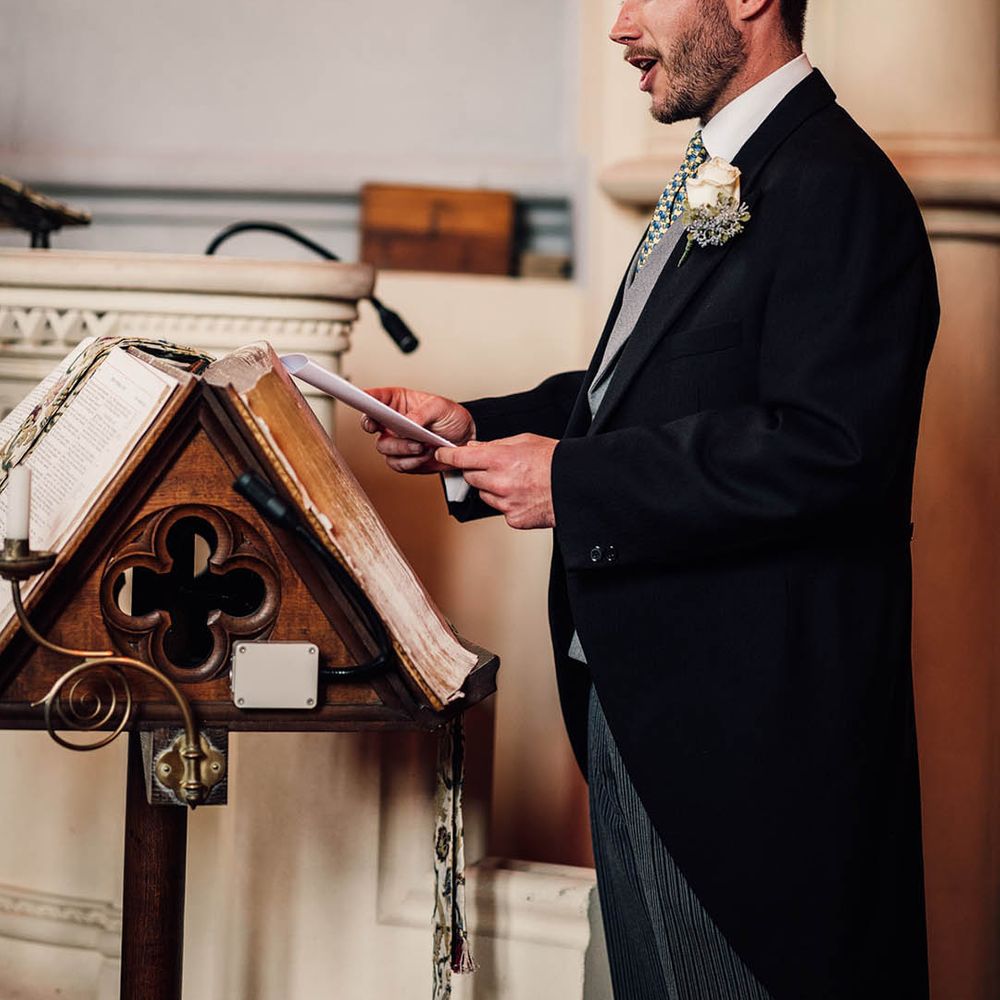 A groomsmen stands at the church to perform a wedding reading 