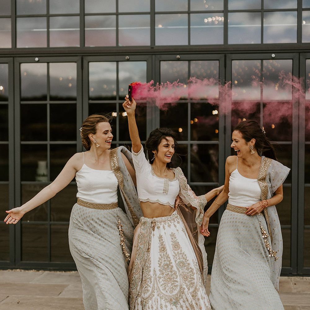 Bride walking with bridesmaids to pink smoke flare for fun wedding bridal party photo
