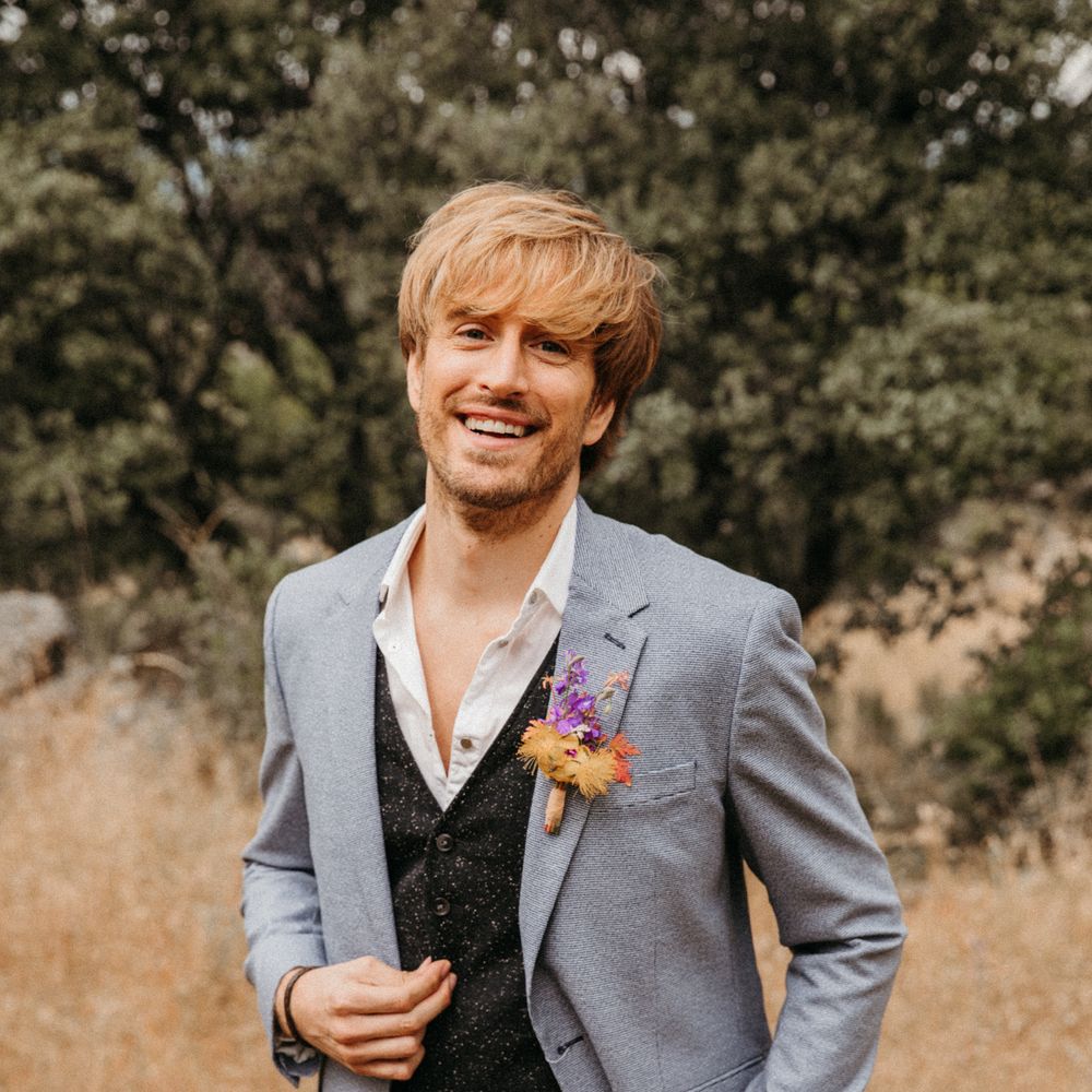 Groom smiles at the camera wearing pastel blue suit and dark waistcoat