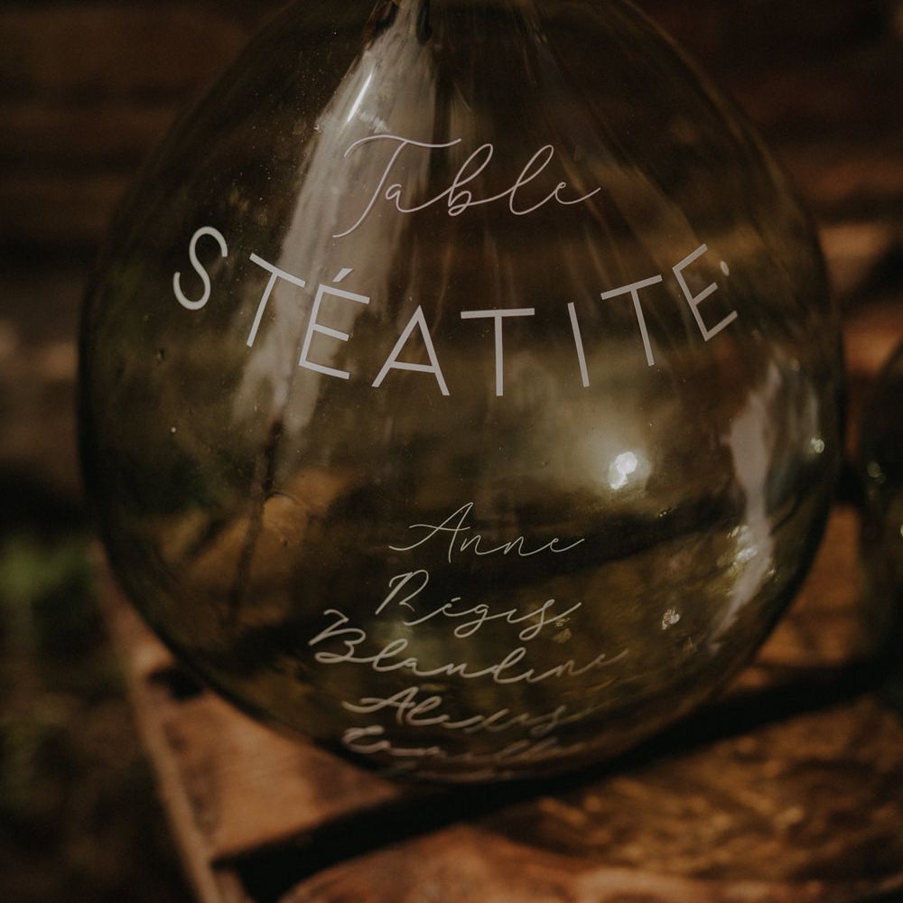 Green apothecary jar written on with white ink for table plan decor 