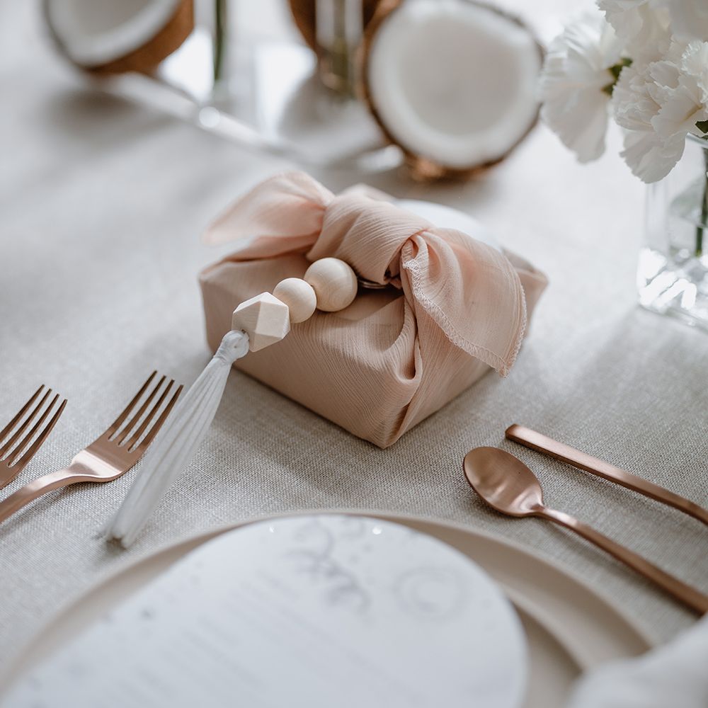 Wedding favour wrapped in a blush fabric with wooden bead detail