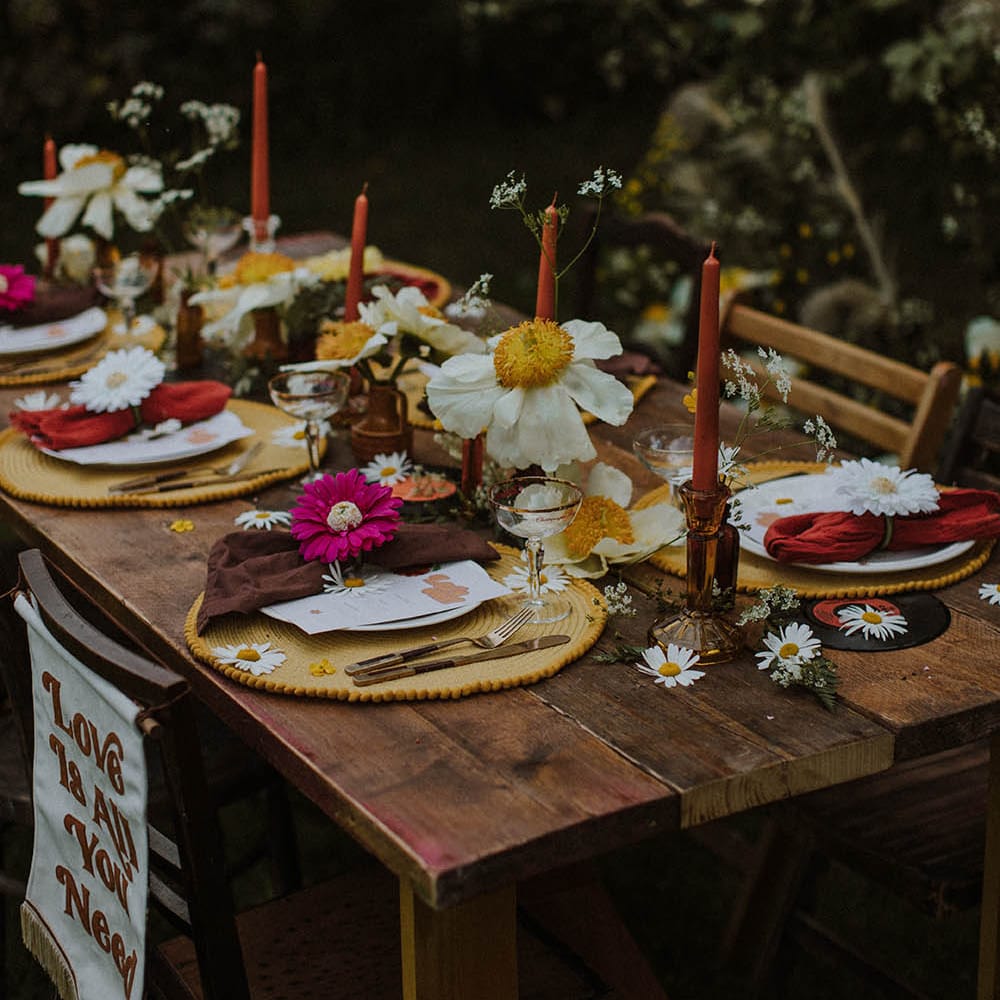 wooden table with red, orange, yellow, brown and gold table decor and flowers 