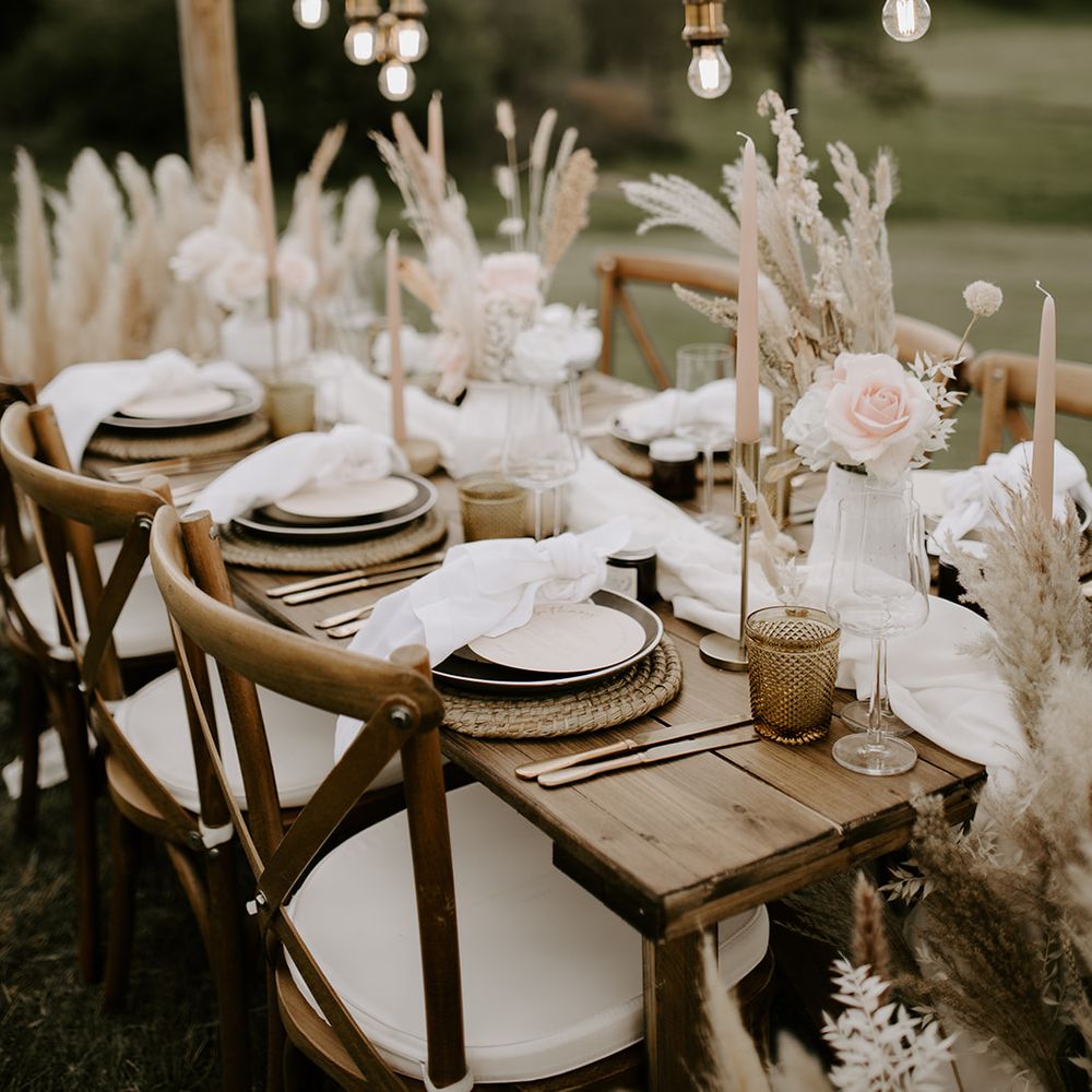 Neutral and pink wedding table decor with wicker place matts, taper candles and light installation 
