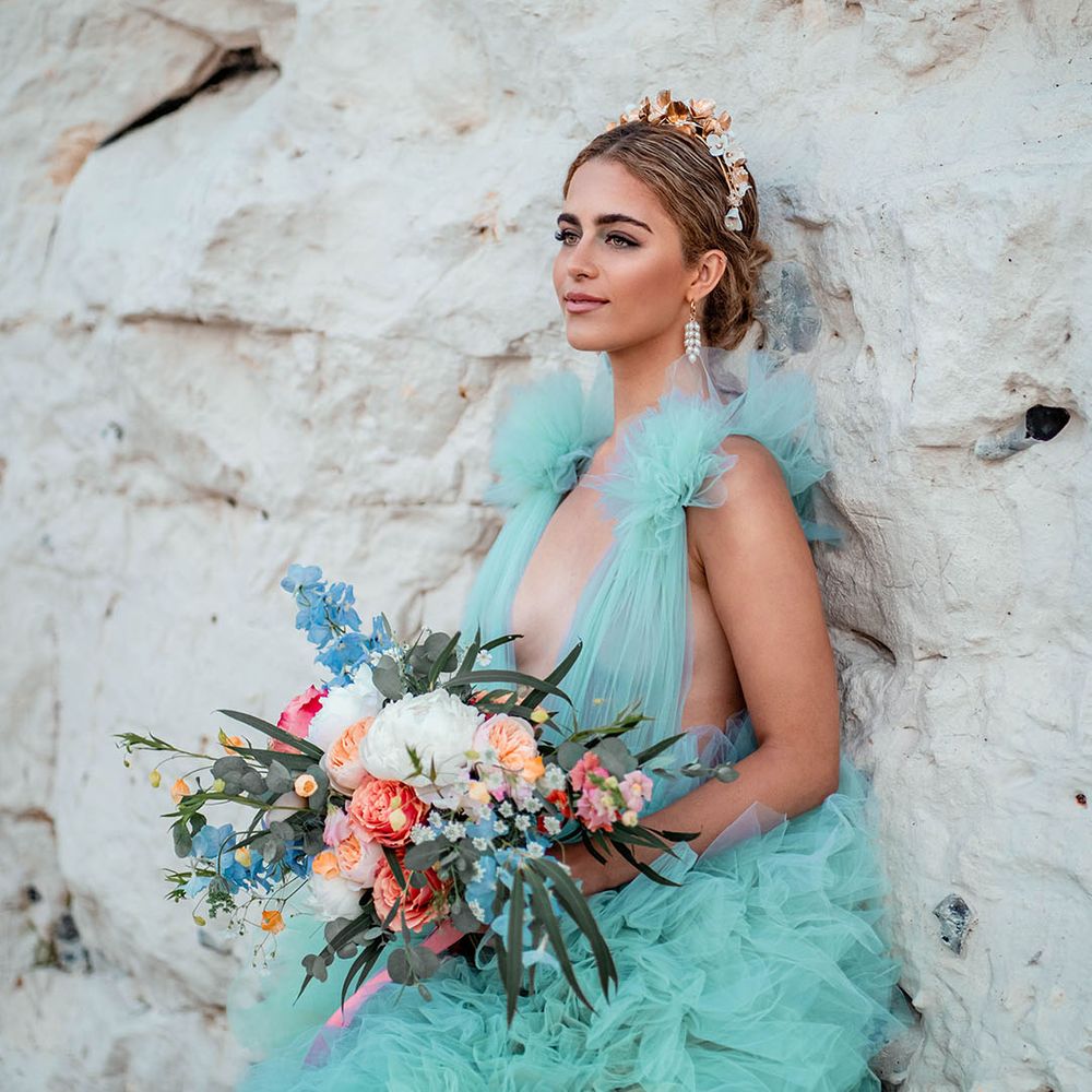Bride in a mint green wedding dress holding a pastel flower bouquet by the rocks at her Botany Bay elopement 