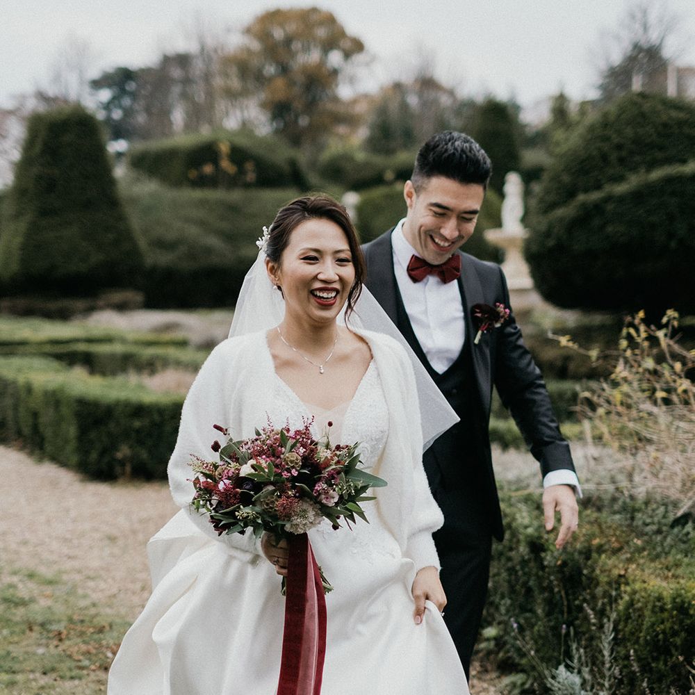 Burgundy bouquet for bride who wears a white cardigan cover up at winter wedding