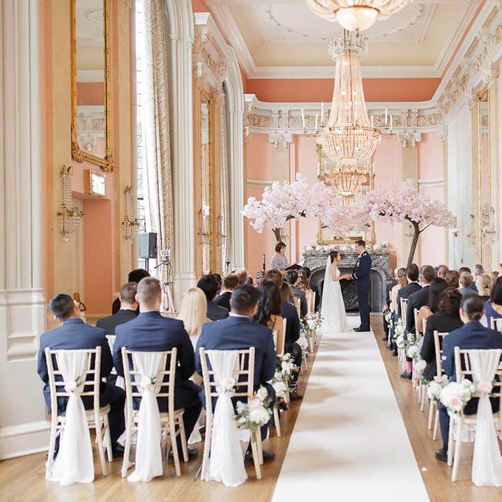 Bride & groom stand under blossom tree archway at Danesfield House