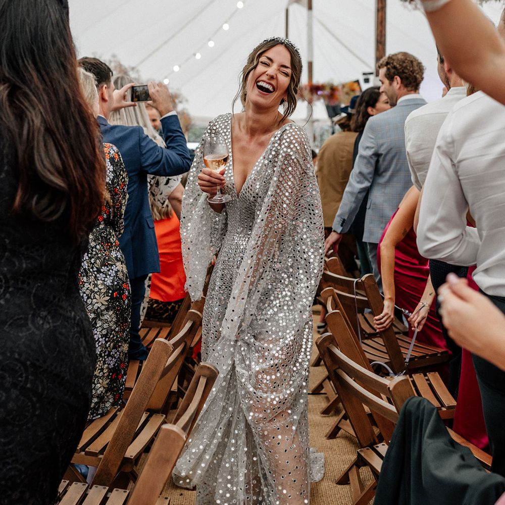 Bride in a silver sequin wedding dress walking through her marquee wedding reception