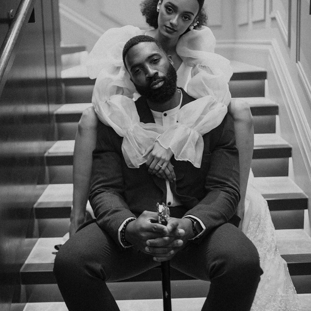 Black bride with an afro middle parting wedding ponytail embracing her husband on the steps at Mayfair Townhouse 
