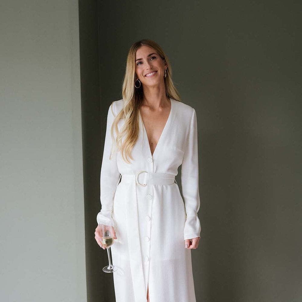 Bride's relaxed white long sleeve and plunging neckline buttoned wedding dress with belt and gold Saint Laurent mules 