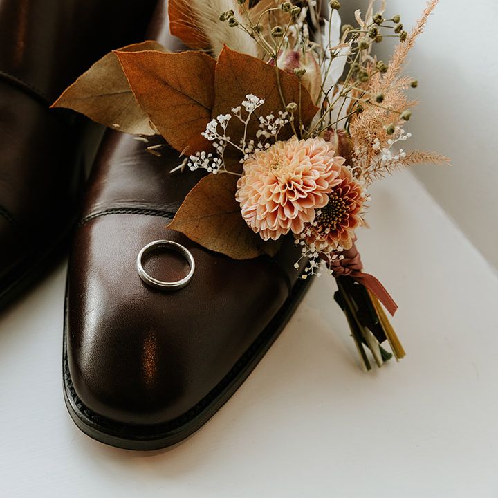 Groom's brown shows with the wedding bands on each shoes and small autumnal bouquet