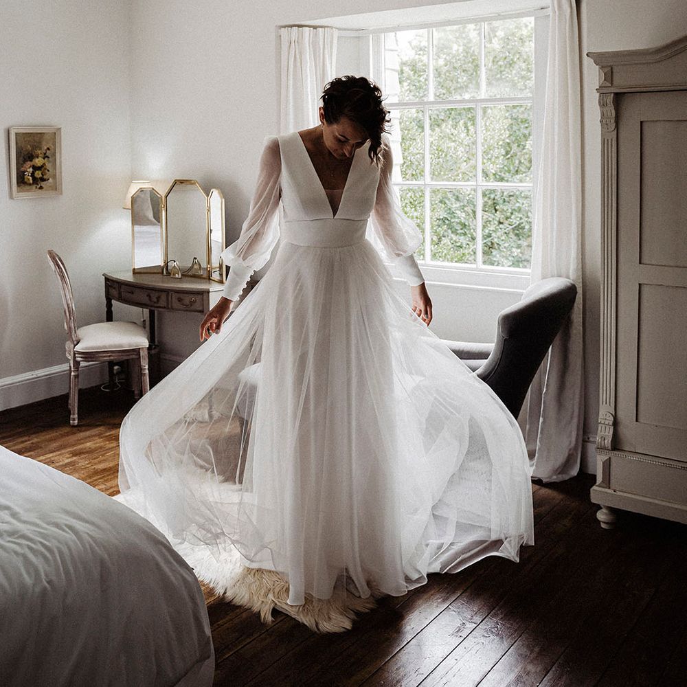 Bride in sheer long sleeve Sassi Holford wedding dress with tulle skirt and button detail 