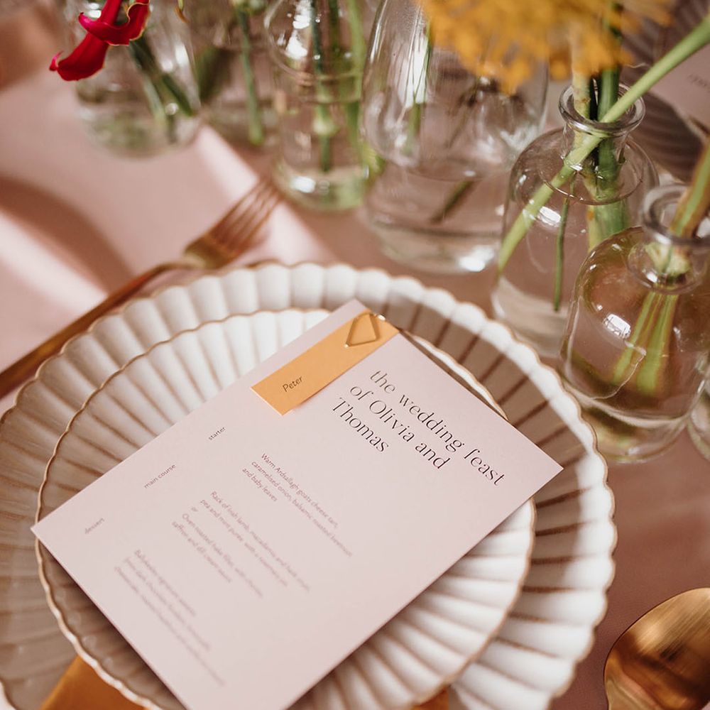 Place setting with scalloped edge plates and contemporary on the day menu stationery cards
