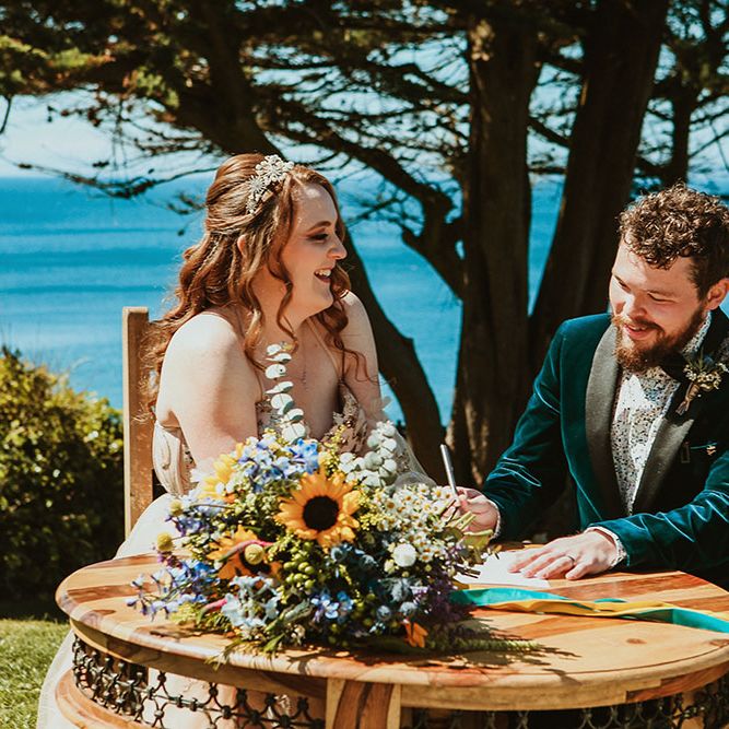 Bride & groom sign wedding certificate on sea front during Cornwall wedding 
