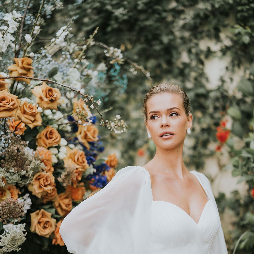 Bride in balloon sleeve wedding dress with pearl earrings with a bun hairstyle 