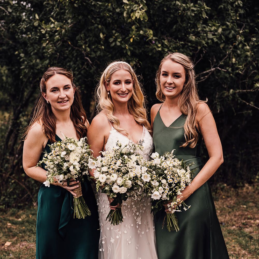 Bride in an applique Alexandra Grecco Lana wedding dress with her bridesmaids in different shades of green satin dresses 