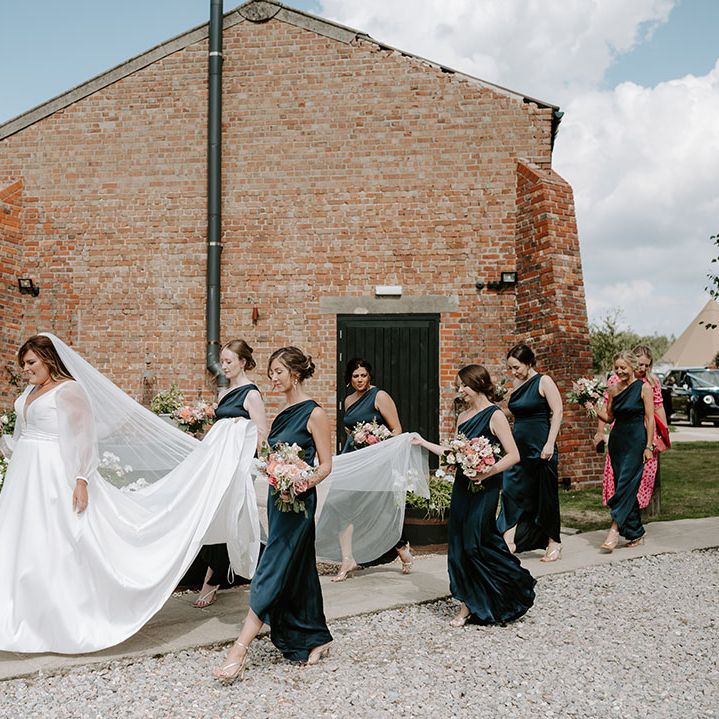 Bridesmaids wear one shoulder satin bridesmaid dresses and carry brides wedding dress train 
