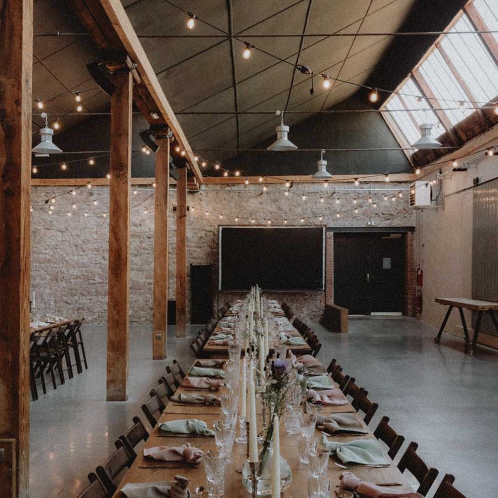 Industrial styled wedding venue with wooden banquet tables and DIY decor 