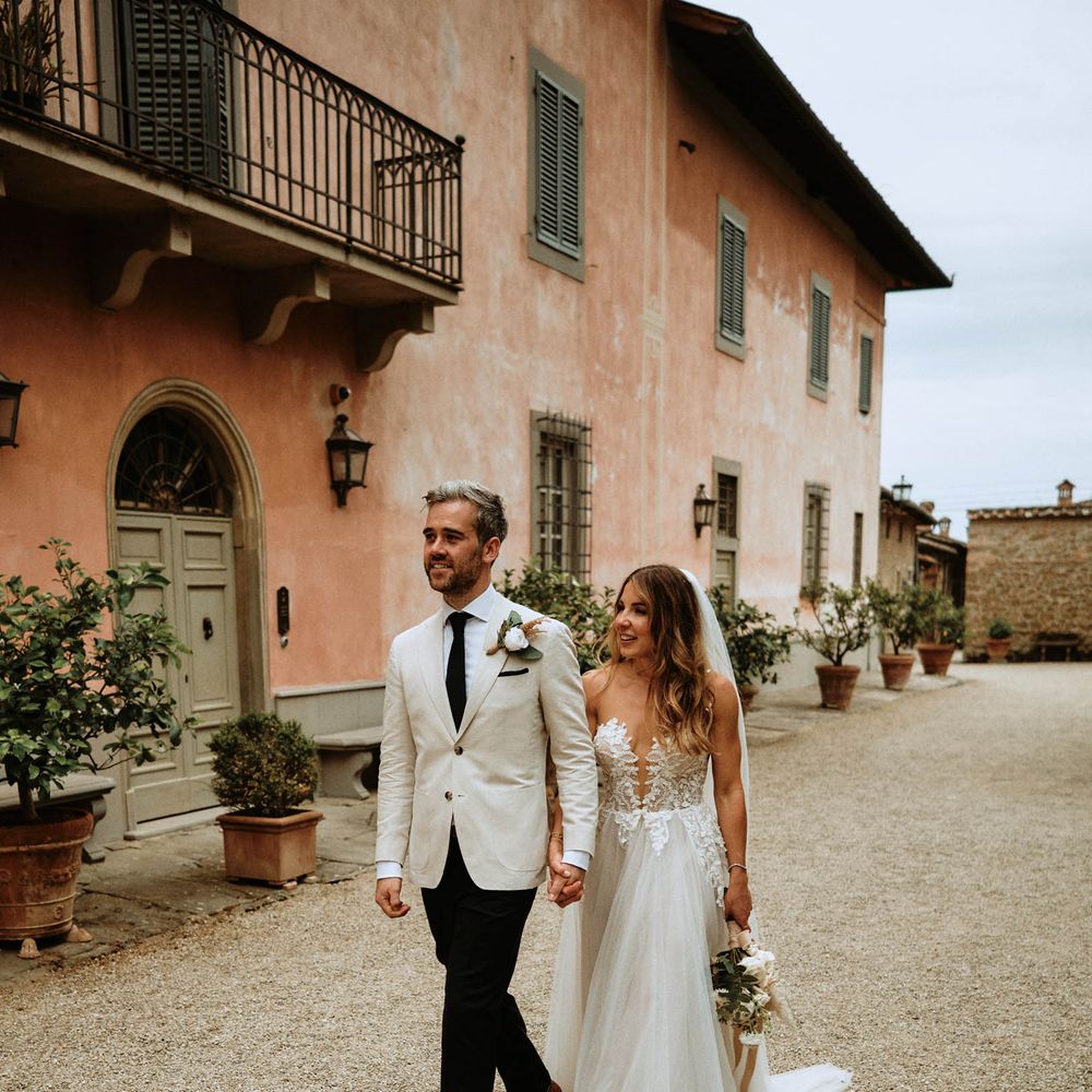 Bride and groom walk hand in hand through italian villa at destination wedding