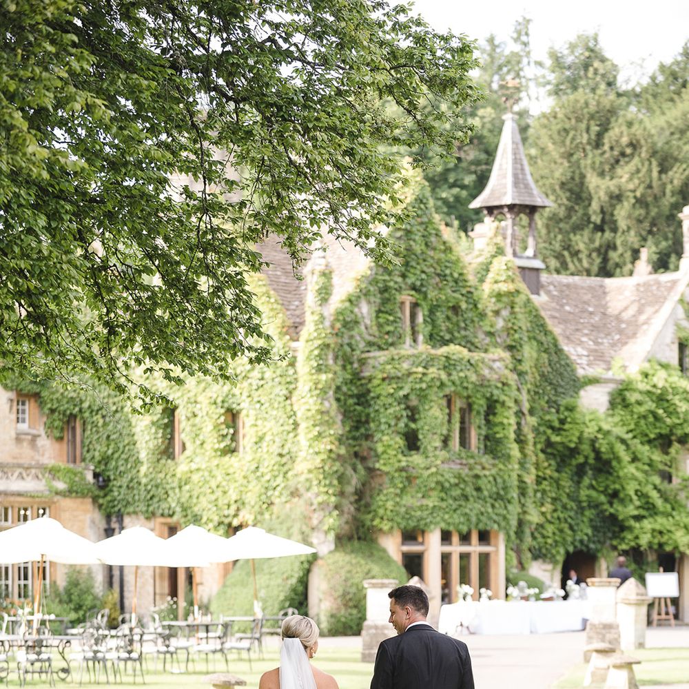 The Manor House, Castle Combe wedding venue with the bride in a fitted mermaid wedding dress and groom in morning suit 