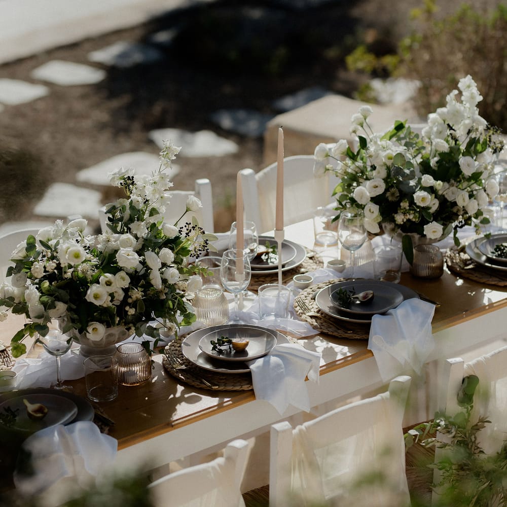 Wedding tablescape with white roses, white berries, italian ranunculous and eucalyptus, figs, ribbed jars and blush tapered candles