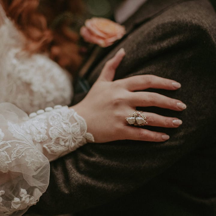 Bride's crystal and silver ring worn by boho bride with white patterned wedding nail art 