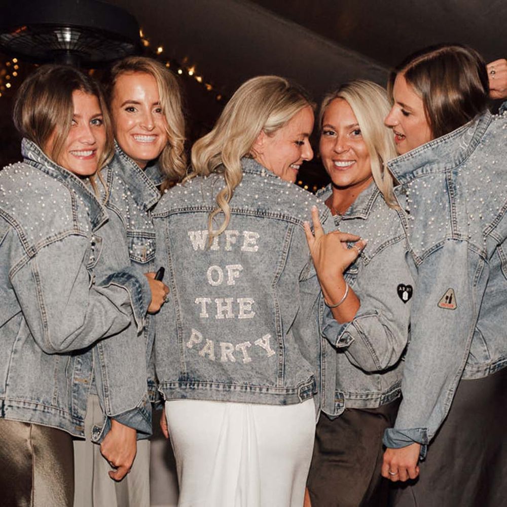 Light blue 'wife of the party' bridal denim jacket with the bridesmaids in matching blue denim cover-ups with pearls on 