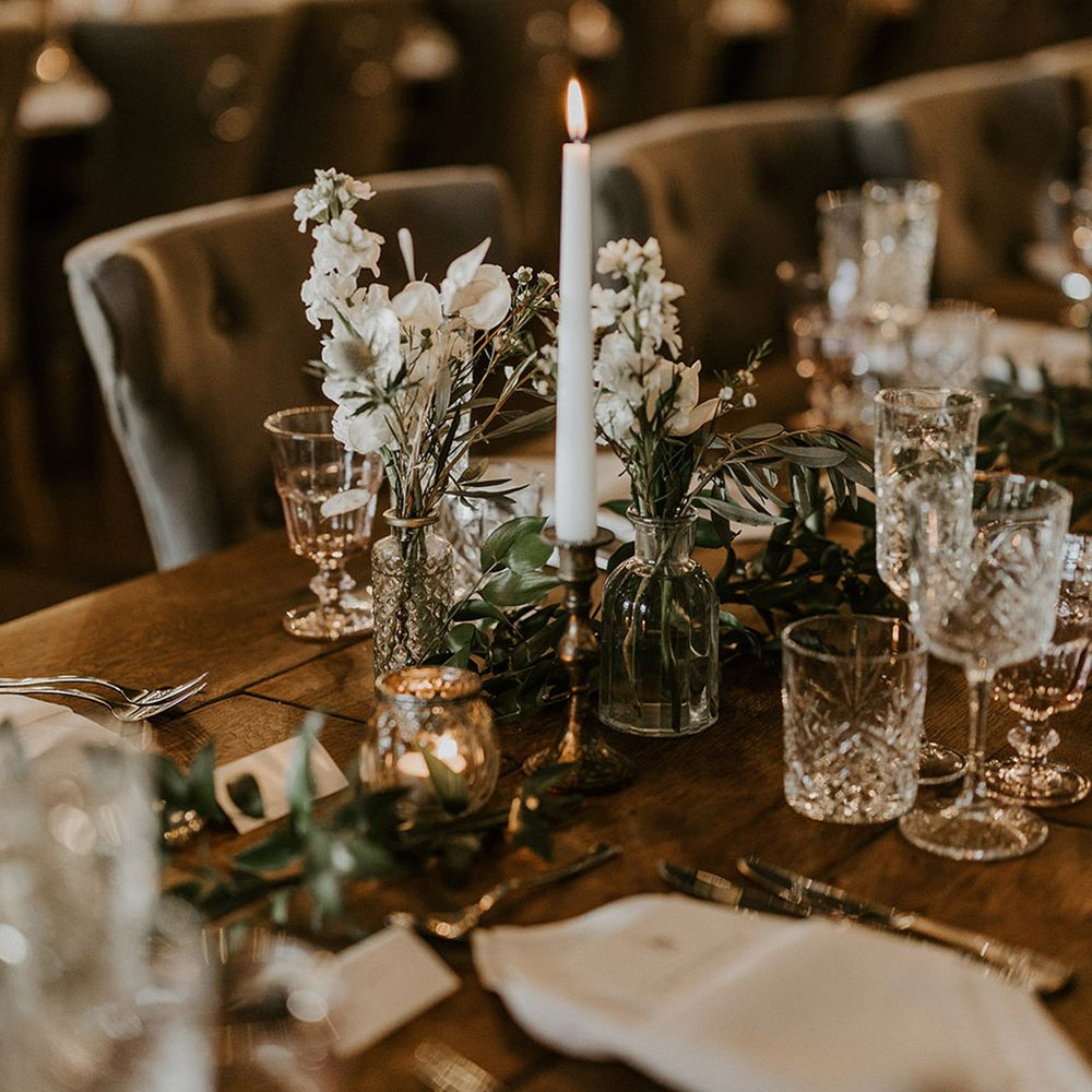 White classic flower arrangements with white candles decorating the tables 