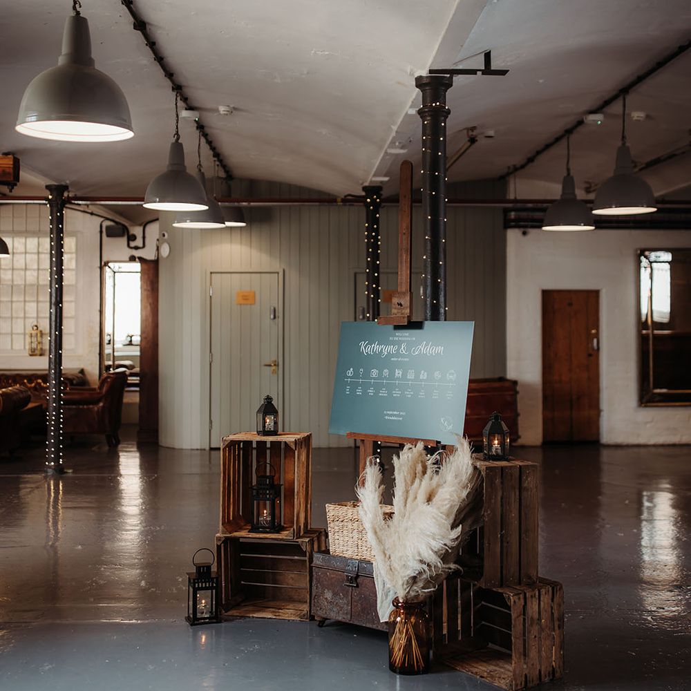 Dark green wedding welcome signage with boho decorations with vases of pampas grass 