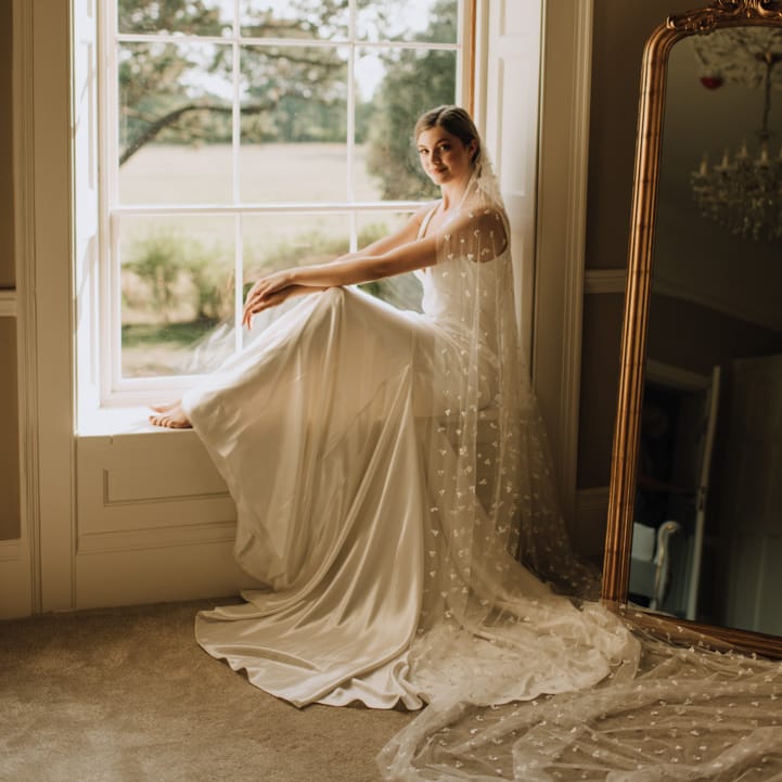 Bride sits beneath Georgian window at Reymerston Hall