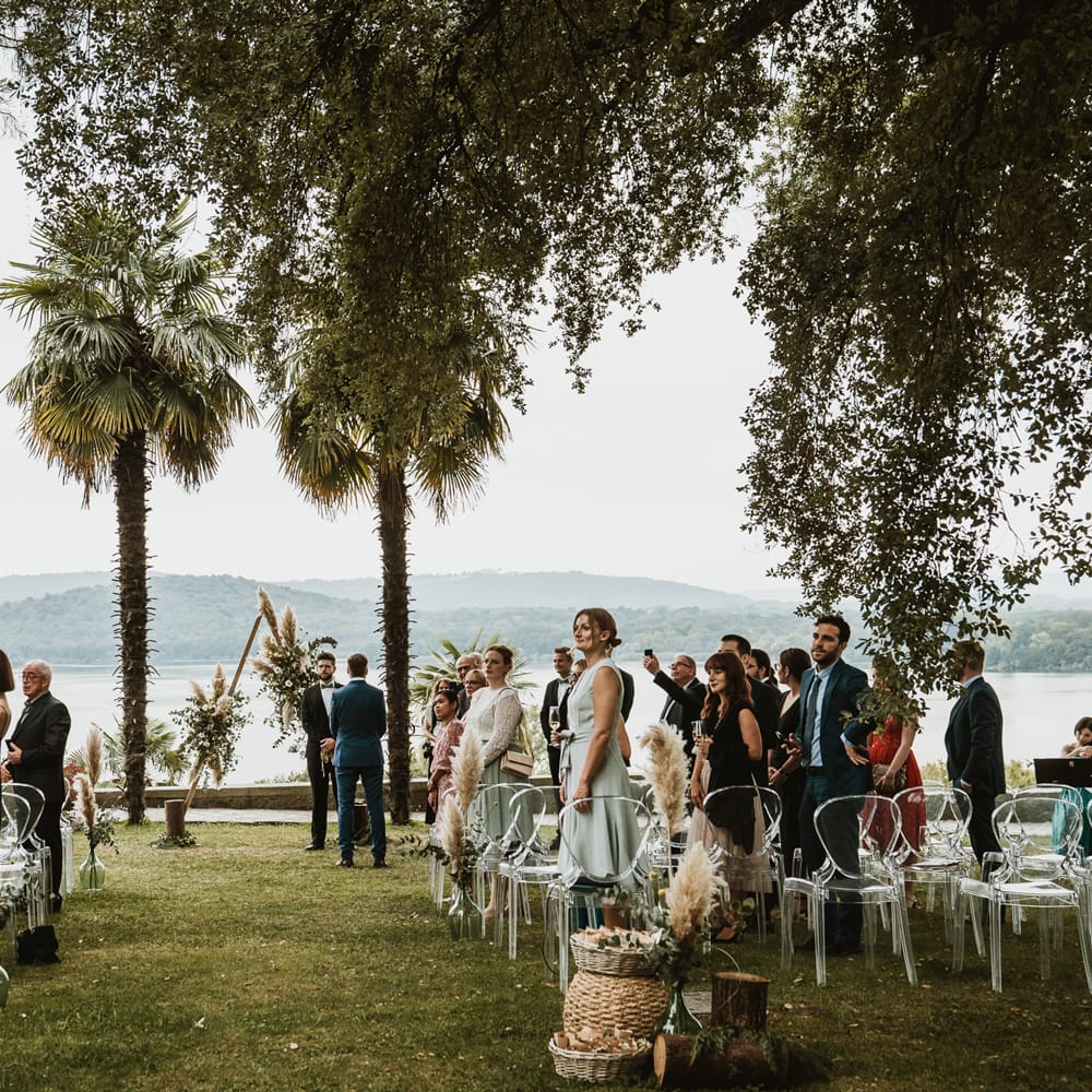Outdoor wedding ceremony at Cella Grande, Lake Viverone, Italy with ghost chairs and pampas grass decor 