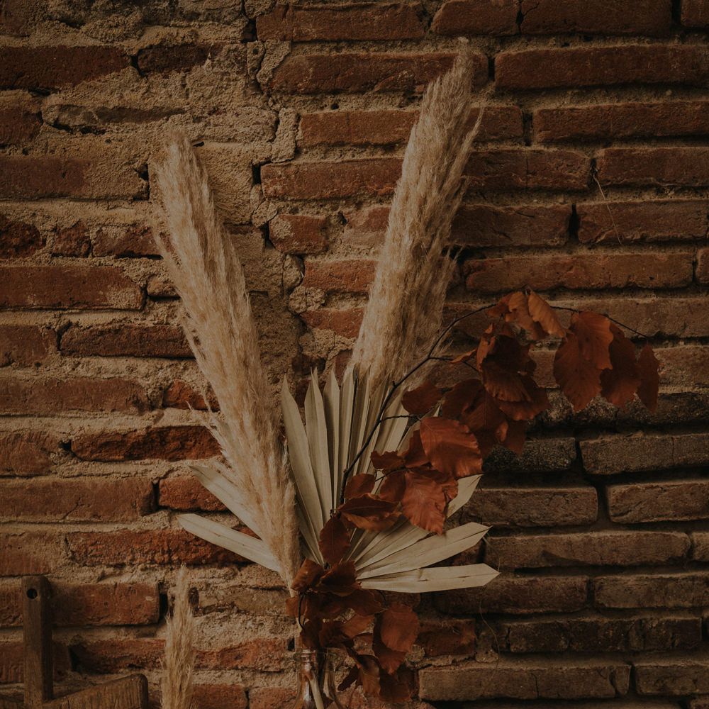 Apothecary jar filled with pampas grass, dried palm leaves and brown foliage 