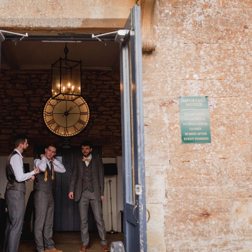 Groom and groomsmen stood in archway of Church before wedding