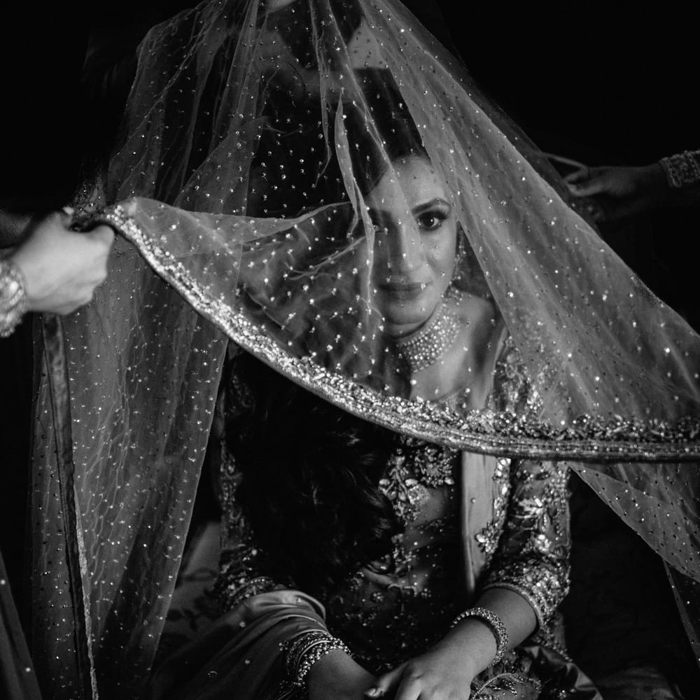 Black & white image of bridal veil being lifted above head