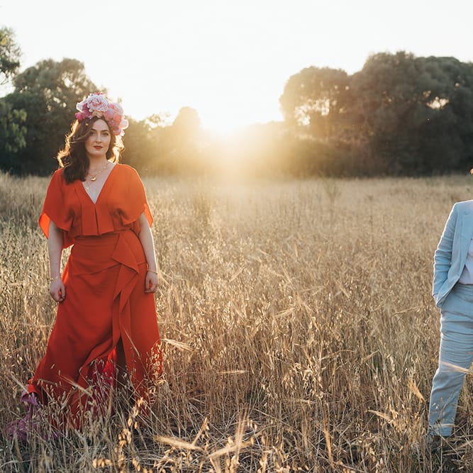 Brides stand apart for post wedding photoshoot as the sun shines behind them during golden hour