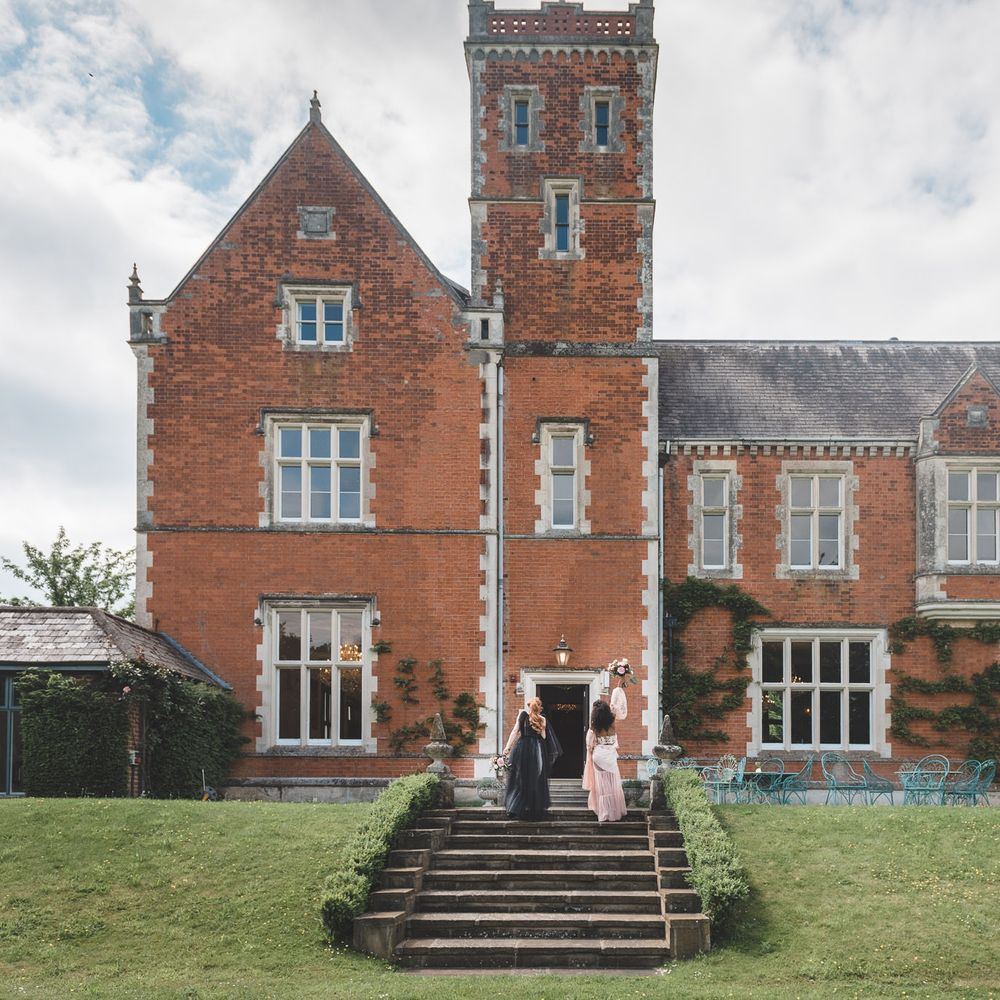 Two brides walking up the steps at Thicket Priory country house wedding venue for Autism marriage inspiration