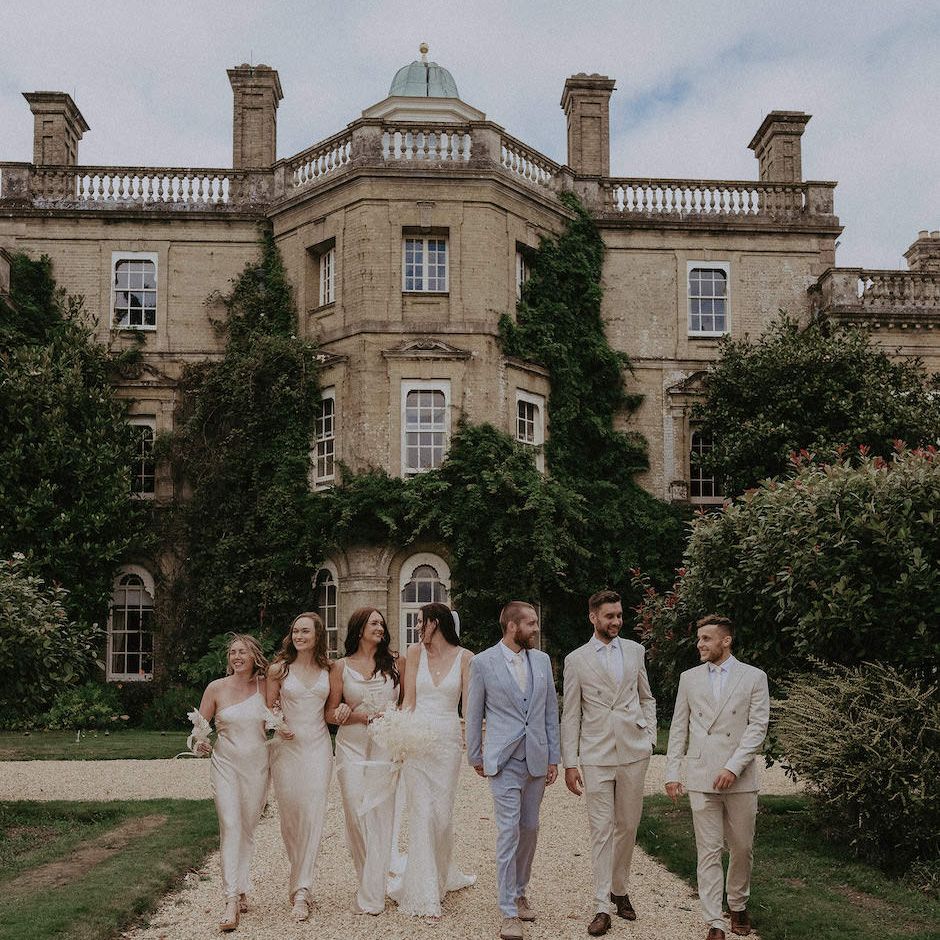 Bridesmaids in champagne dresses with groomsmen in cream wedding suits