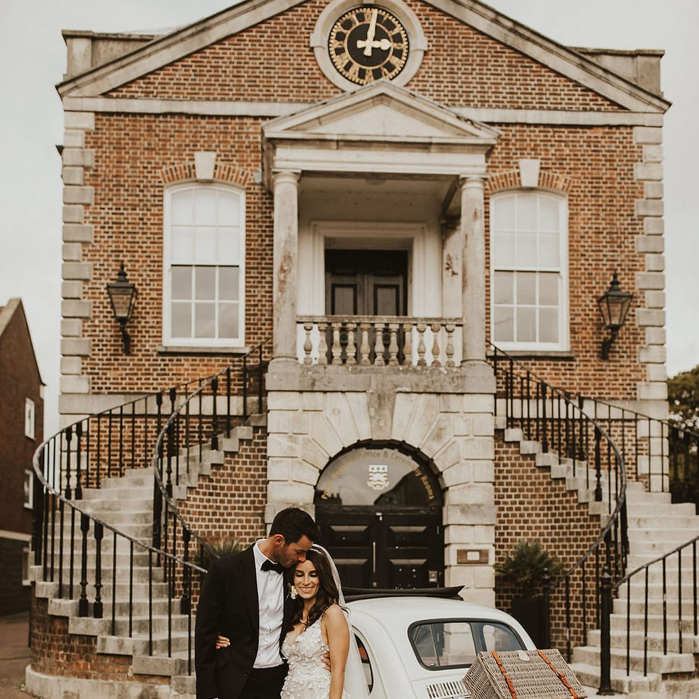 Bride & groom stand beside vintage Fiat 500 car 