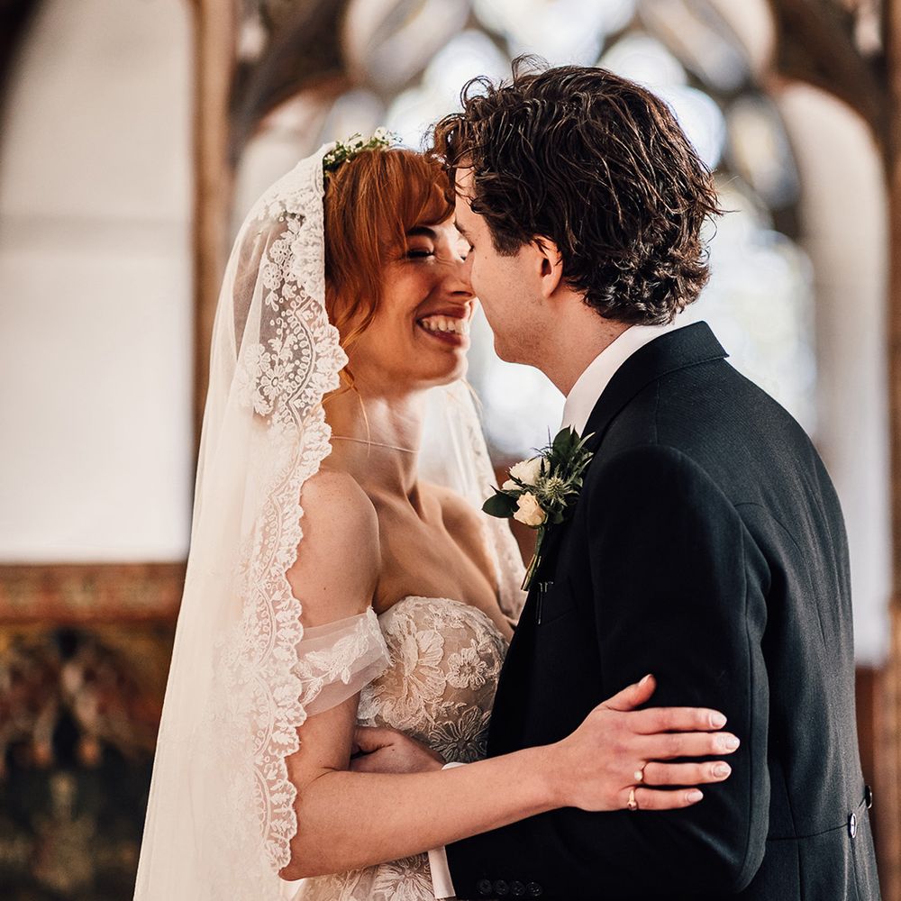 Bride in off the shoulder wedding dress kisses groom at Oxnead Hall wedding