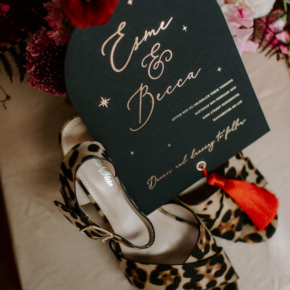 Black wedding invitation with gold foil lettering and red tassel 