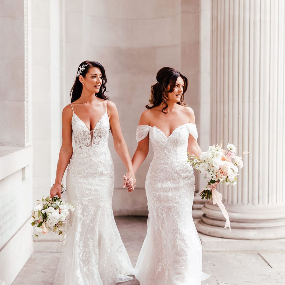 Two brides at Old Marylebone Town Hall wedding in an off the shoulder wedding dress and fishtail wedding dress with thin straps 