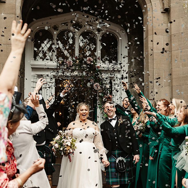 Wedding guests cheer and celebrate by throwing black circle confetti for the newlyweds