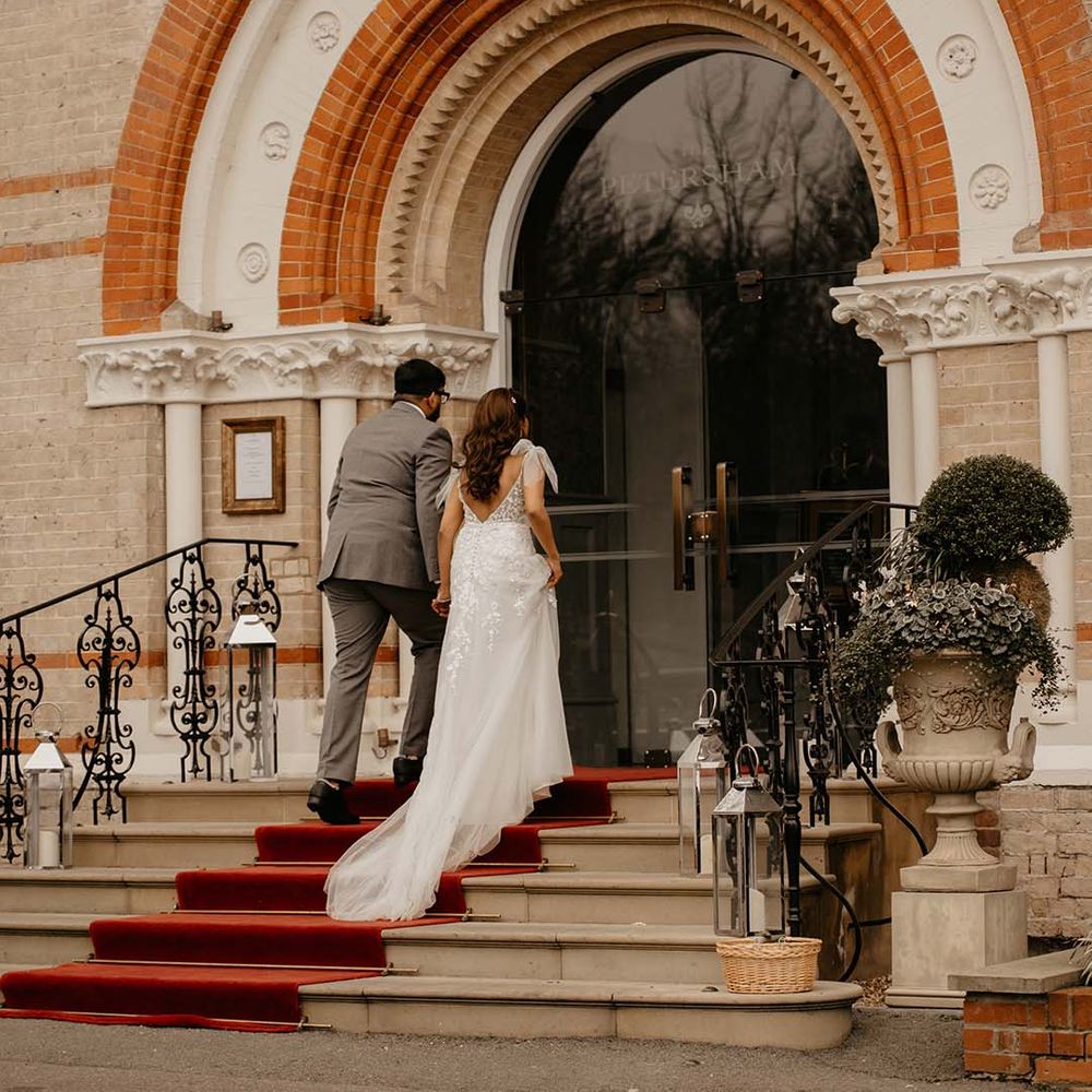 Bride and groom under large exposed orange and neutral brick arch at The Petersham Hotel in Richmond