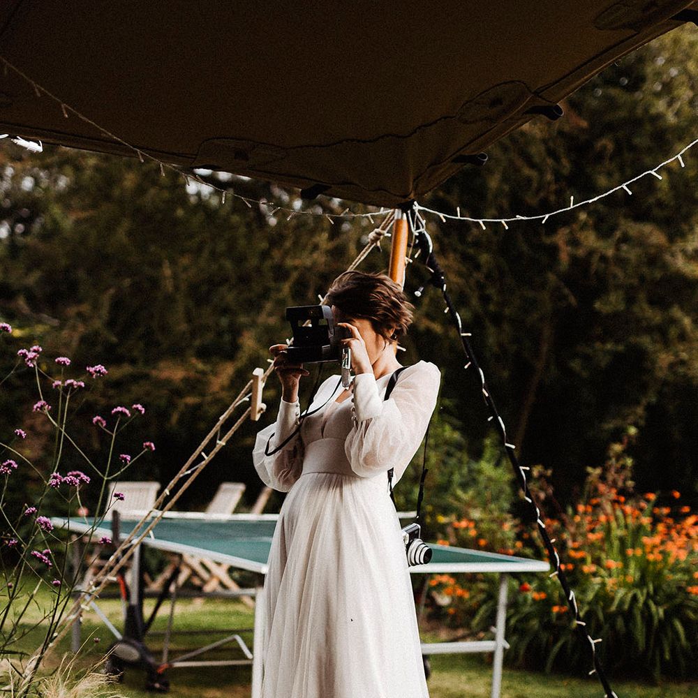 Bride takes her own pictures on her wedding day wearing sheer long sleeve gown with button detail