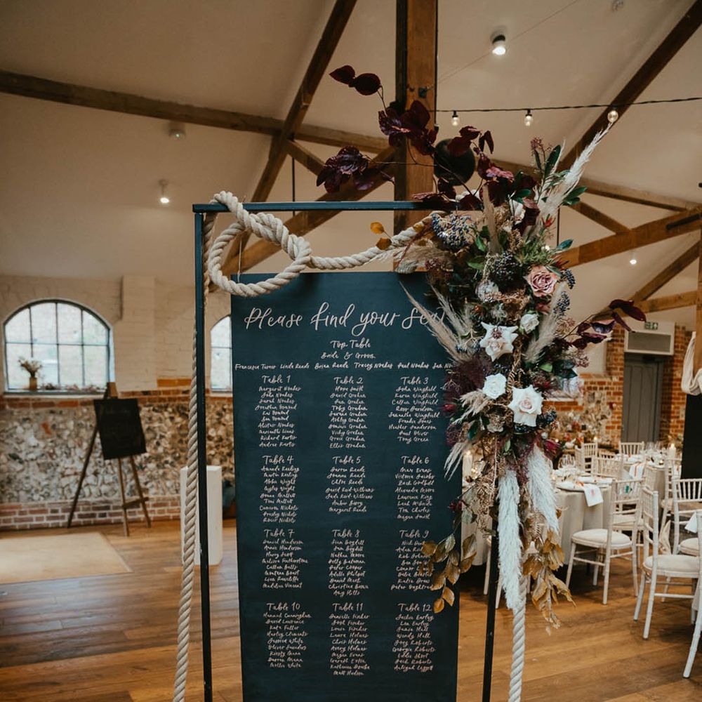 Black wedding table plan/seating chart sign decorated with rope and autumnal wedding flowers 