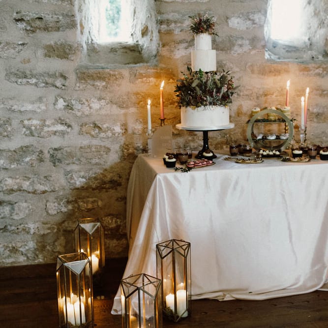 Wedding cake table decorated with candles, lanterns and acrylic signs 