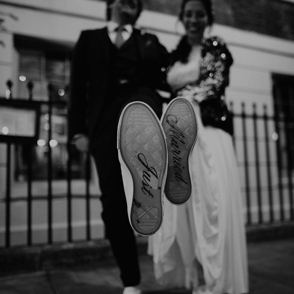 Bride and groom wearing matching customised converse with "just married" written on the soles 